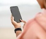 Close-up of a woman interacting with a touchscreen phone outdoors.